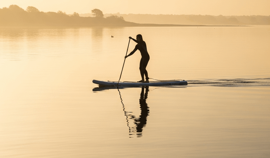 stand up paddleboarder gliding across glassy calm water at s 20260529 232333