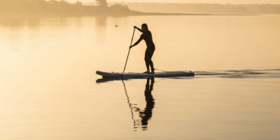 stand up paddleboarder gliding across glassy calm water at s 20260529 232333
